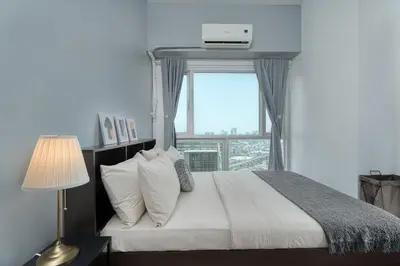 a bedroom with a large bed with a window at Free Parking! Beautiful 2BR Home in Central Makati in Manila