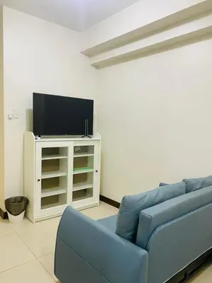 a living room with a blue couch and a tv at Urban Resort District in Manila