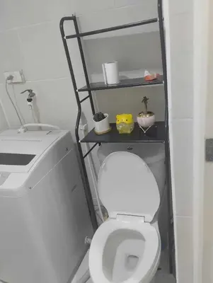 a bathroom with a toilet with a shelf above it at Bini Comfort room in Manila