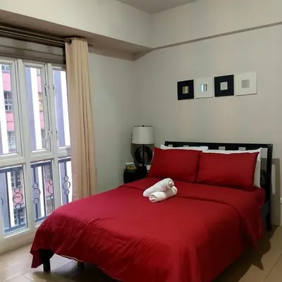 a teddy bear is sitting on a red bed at Cozy Jen 150newport Boulevard condotel in Manila