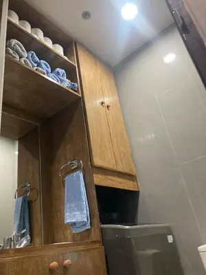 a kitchen with wooden cabinets and a toilet at Rustic condo in Makati CBD in Manila