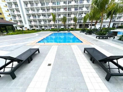 a swimming pool with benches and a large building at CASA Salcedo - Field Residences in Manila