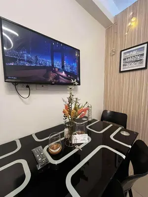 a room with a table with a television on the wall at Affordable Condo staycation near MOA ,NAIA & Airport 4 GUESTS WIFI,NETFLIX,POOL in Manila