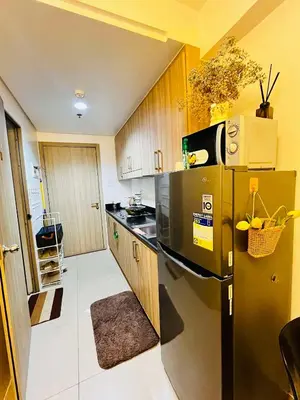 a kitchen with a black refrigerator and wooden cabinets at Affordable Condo staycation near MOA ,NAIA & Airport 4 GUESTS WIFI,NETFLIX,POOL in Manila
