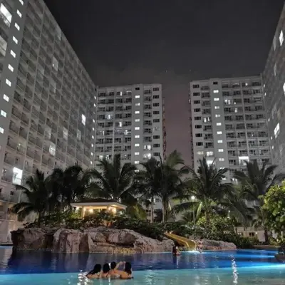 two people swimming in a pool in a city at night at Snuggle Suites in Manila