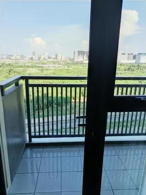 a room with a balcony with a view of a field at Near MOA 3 pax unit in Gentry Manor in Manila