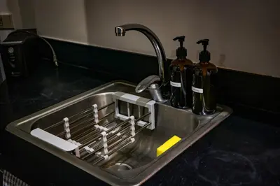 a kitchen sink with two bottles in it at Snug Stay in Gramercy Makati with City Skyline View! in Manila