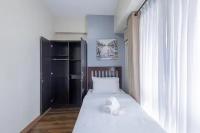 a bedroom with a bed with white sheets and a window at NEW 2BR Family Home with FREE Parking & Fiber Wi-Fi in Manila