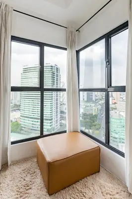 a room with large windows with a ottoman in front at Kael Studio in Manila