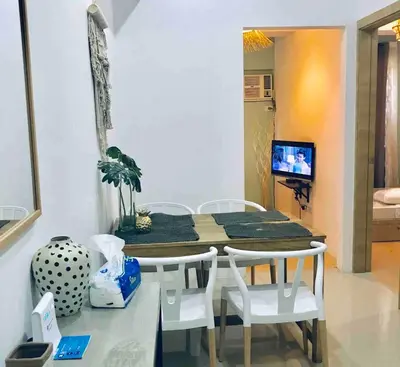 a dining room with a table and white chairs at Modern Tropical Home In The Heart of Quezon City in Manila