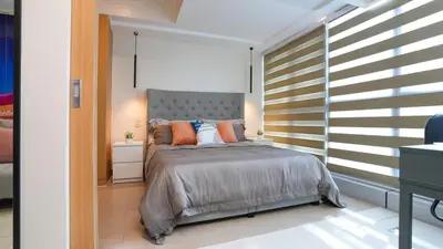 a bedroom with a large bed with orange pillows at Best 1BR in Uptown BGC - Near Mitsukoshi & Malls in Manila
