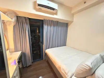 a bedroom with a bed and a window with a television at Comfy Makati Condo Wifi, Netflix and Disney in Manila