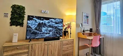a living room with a flat screen tv on a wooden cabinet at The Cozy Hub Studio with Wifi Near Eastwood City in Manila
