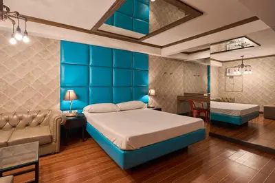 a bedroom with a blue bed and a couch at Victoria Court Hillcrest in Manila