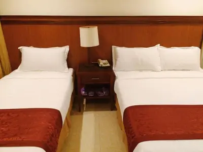 a hotel room with two beds and a night stand at Chinatown Lai Lai Hotel Inc in Manila