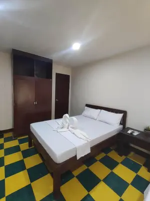 a bedroom with a bed with white sheets and a checkered floor at Manalo Resort Hotel in Tutulo