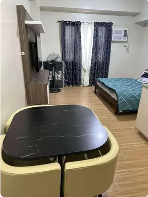 a room with a table and a bed in it at Tulip Garden Apricot Bldg 1BR with pool and Gym in Biñan