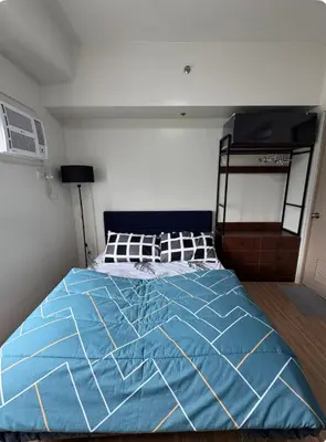 a bed in a bedroom with a blue comforter at Tulip Garden Apricot Bldg 1BR with pool and Gym in Biñan
