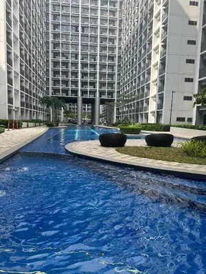 a large pool of blue water in front of tall buildings at Sweet Staycation in Manila