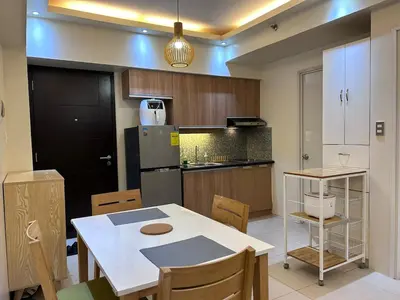 a kitchen with a table and chairs and a refrigerator at Rolly's Place in Manila