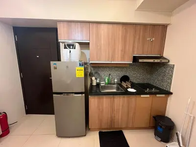 a small kitchen with a refrigerator and a sink at Rolly's Place in Manila