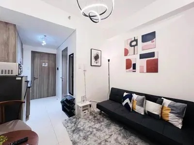 a living room with a black couch in a room at 1-bedroom with balcony in Manila
