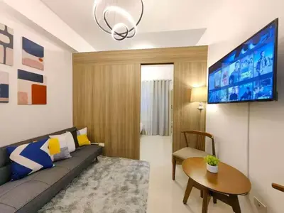 a living room with a couch and a table and a tv at 1-bedroom with balcony in Manila