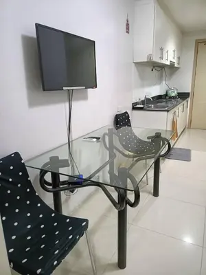 a glass table with two chairs and a flat screen tv at Roiden Sea Residences in Manila
