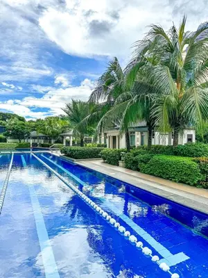 a swimming pool with blue water and palm trees at Studio Suite at Fairway Terraces near NAIA T3 in Manila