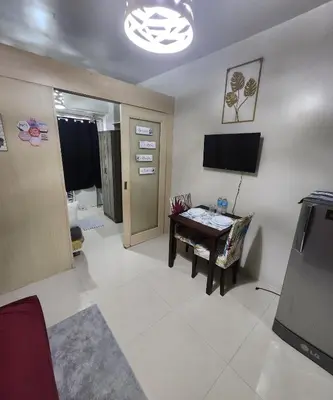 a living room with a table and a television at MNM Place in Manila