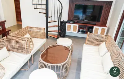 a living room with wicker chairs and a television at Asana Amadeo a private villa near Tagaytay in Amadeo