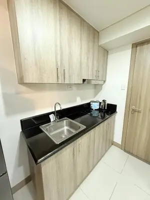 a kitchen with a sink and wooden cabinets at Comfortable Cozy Staycation in Manila