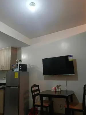 a kitchen with a table and a television on the wall at SHORE 2 Residences by ASKrentals in Manila