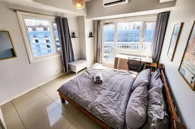 a bedroom with a bed and two windows at Amazing City View 2br apartment in Makati - 70sqm in Manila