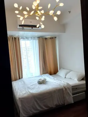 a bedroom with a bed with a chandelier at City Scape Comforts Makati in Manila