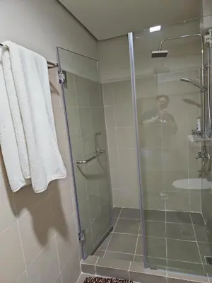 a shower in a bathroom with a man taking a picture at Condo next door 3 in Manila