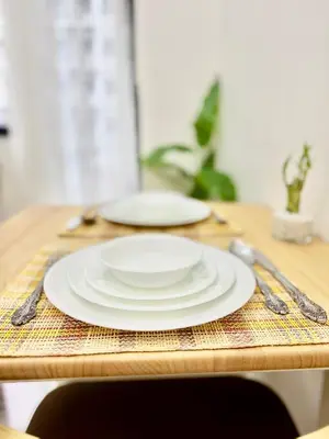 a table with two white plates on a wooden table at Minimalist Chic Condo near MOA-Shore3 Tower2 in Manila