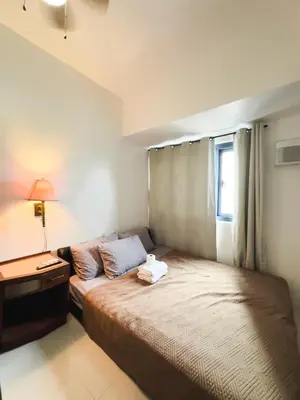 a bedroom with a bed and a desk and a window at The Embassy Pods in Manila