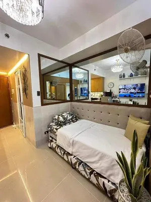 a bedroom with a large bed and a kitchen at Condo near MOA and NAIA in Manila