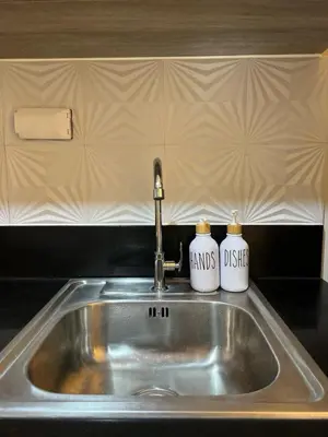 a kitchen sink with two mugs on top of it at S residence, Mall of Asia Area in Manila
