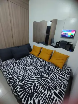 a bed with a black and white comforter in a room at Cozy Apartment in Mall of Asia in Manila