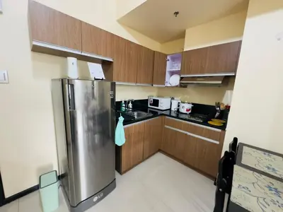 a kitchen with wooden cabinets and a stainless steel refrigerator at 1 BEDROOM Staycation in Pasay in Manila
