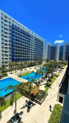 a large apartment building with a pool and palm trees at Sea Residences Tower E in Manila