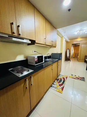 a kitchen with wooden cabinets and a microwave at Shell Residences Tower A in Manila