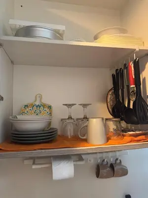 a kitchen shelf with plates and utensils on it at Cozy Flat in Pasay City in Manila