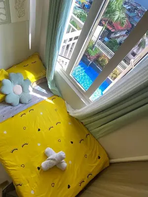 a small bedroom with a yellow bed and a window at Cozy Flat in Pasay City in Manila