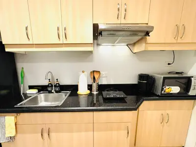 a kitchen with a sink and a microwave at Free Car Parking - Sheridan North 1BR Apt near BGC in Manila