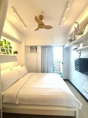 a bedroom with a large bed with a ceiling fan at Free Car Parking - Sheridan North 1BR Apt near BGC in Manila