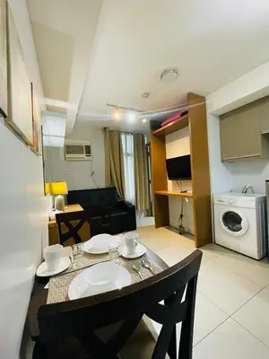 a kitchen and living room with a table and chairs at Cozy 1 Bedroom Condo Unit in Manila