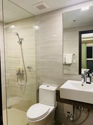 a bathroom with a shower and a toilet and a sink at Savvy Suites Combined 6BR near Okada in Manila